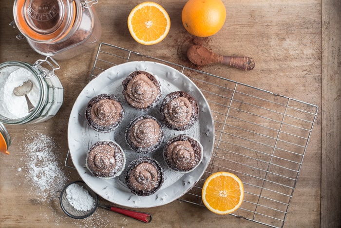 whit plate with muffins and swirls of chocolate orange buttercream frosting and baking mess around