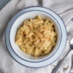 Simple white bowl of homemade mac and cheese with a muted grey background