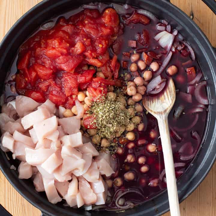 raw ingredients inside a black pan for making chicken and chorizo stew