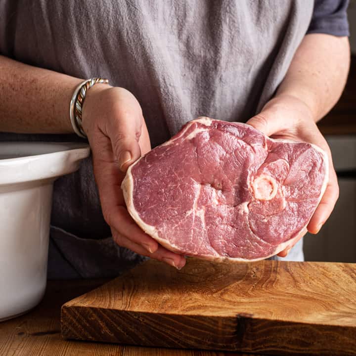 womans hands holding joint of lamb ready to go in slow cooker