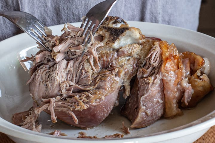 close up of 2 forks shredding tender, slow cooked pulled lamb