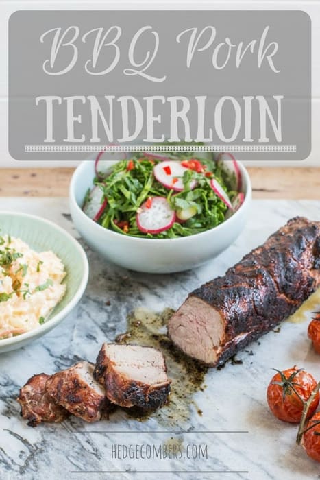 Juicy bbq pork tenderloin sliced on marble slab with bowls of salad and roast tomatoes