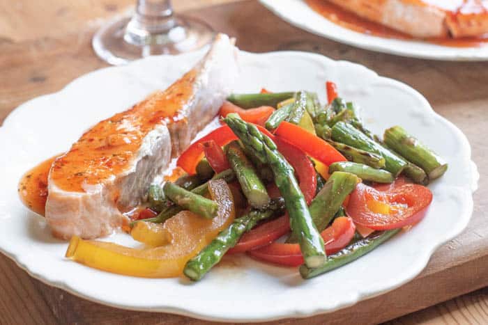 White plate with salmon fillet and asparagus stir fry