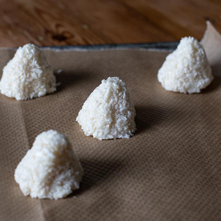 wooden kitchen counter with baking tray and three coconut pyramid cakes about to be baked