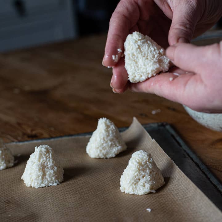 womans hand forming coconut into pyramids or haystacks