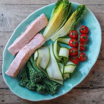 turquoise plate with grilled lettuce, cherry tomatoes, broccoli and 2 pieces of steamed salmon with green dressing