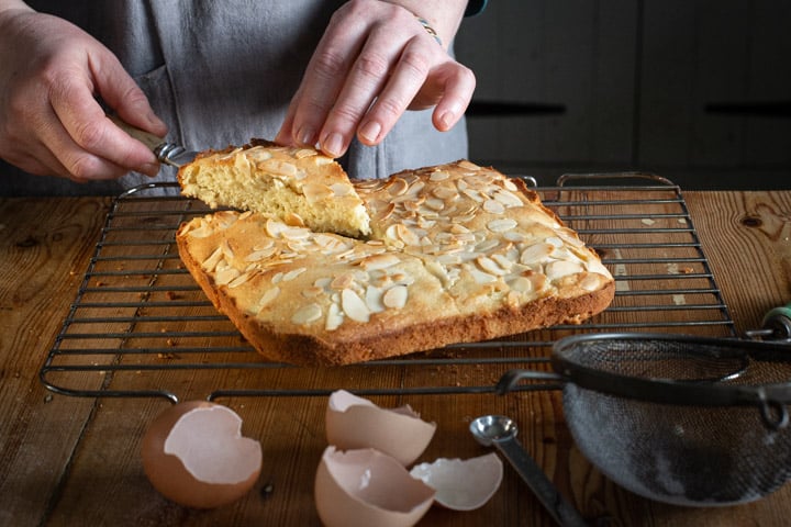 womans hands holding a piece of freshly baked almond cake 