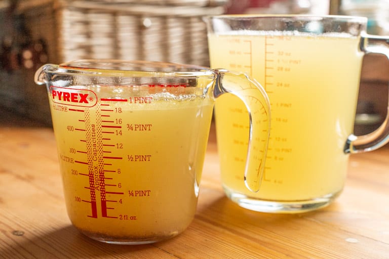 wooden background with 2 jugs of homemade chicken stock