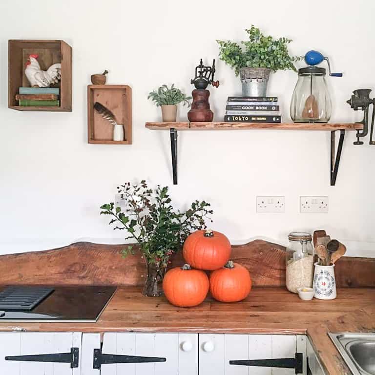 rustic style kitchen with rustic kithchenalia and a wooden counter with three large orange pumpkins ready to make dairy free pumpkin soup