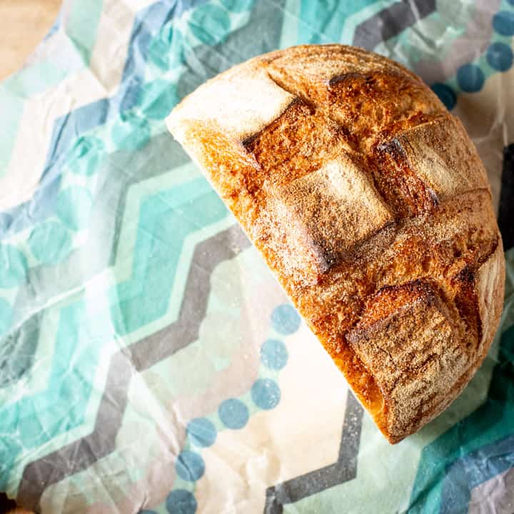 half a round loaf of sourdough bread sitting on blue homemade beeswax wraps