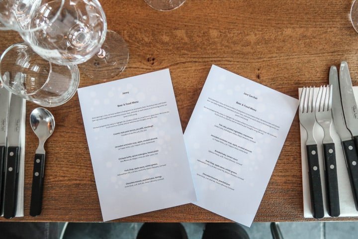 wooden table with silverware, glasses and two personalised menus