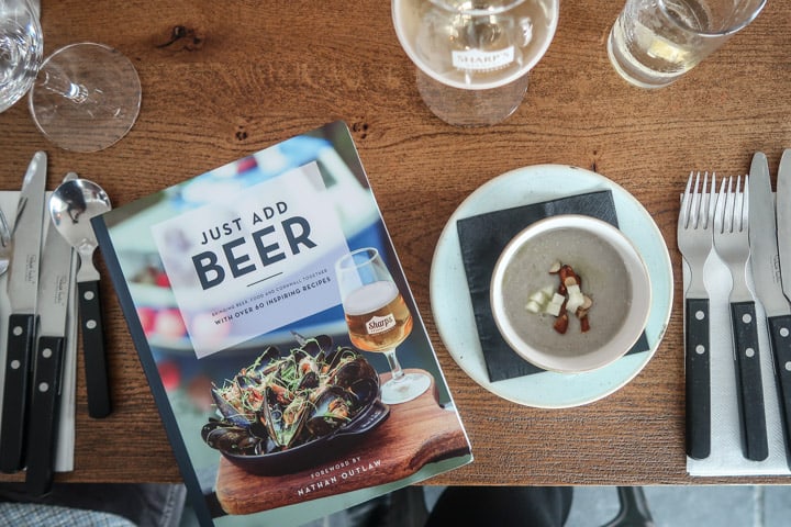 wooden table with silverware and a copy of Just Add Beer cookbook at the Padstow Christmas Festival