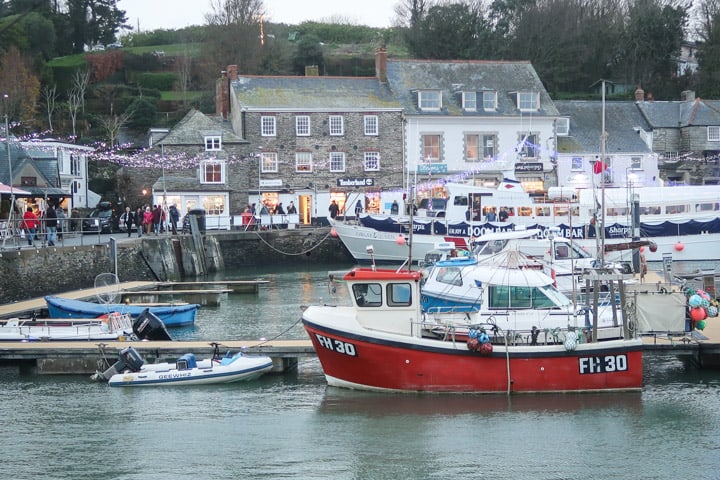 harbour shot at padstow christmas festvival with fishing boats, fairy lights and crowds in teh background