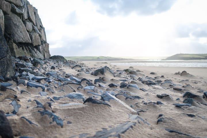 beach scene with wind whipping sand over pebbles at Rock, Cornwall