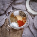 glass jar filled with various spices ready to mix into a homemade fajita seasoning