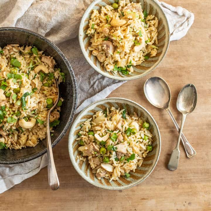 wooden board with 3 bowls filled with my easy chicken biryani recipe