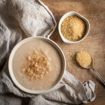 rustic white bowl filled with easy stovetop rice pudding and sprinkled with brown sugar and cinnamon