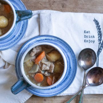 white cloth with blue blue filled with slow cooker Irish stew and 2 spoons