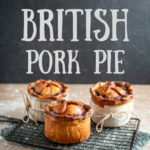 3 handmade British pork pies cooling on a wire rack over a wooden board