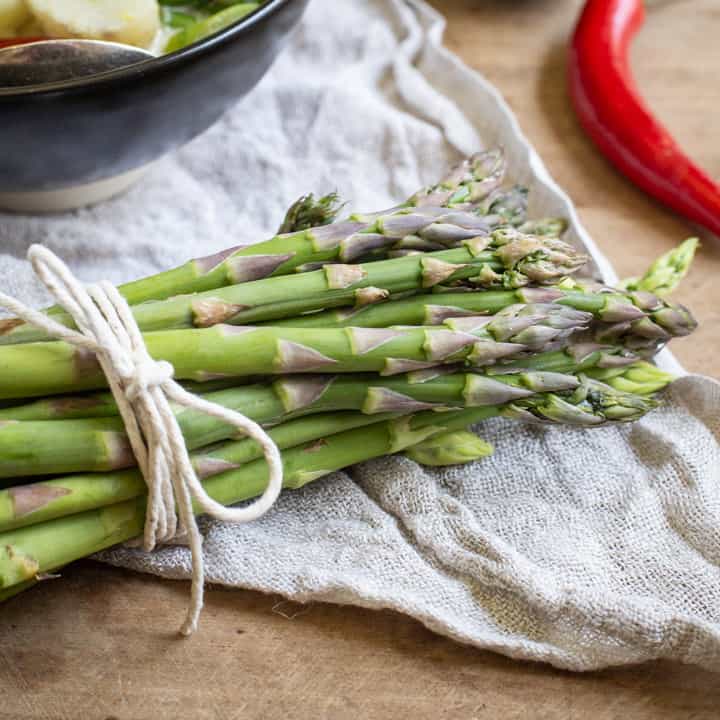 bunch of fresh asparagus tied with butchers string on a piece of natural linen