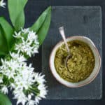 slate background with bowl of homemade Ramsons Pesto and some ramson flowers