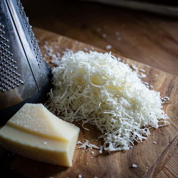 wooden board with small pile of grated parmesan cheese