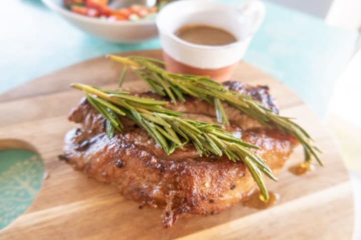 white plate on blue table with a juicy sliced sirloin steak and salad