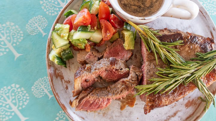 white plate on blue table with a juicy sliced sirloin steak and salad