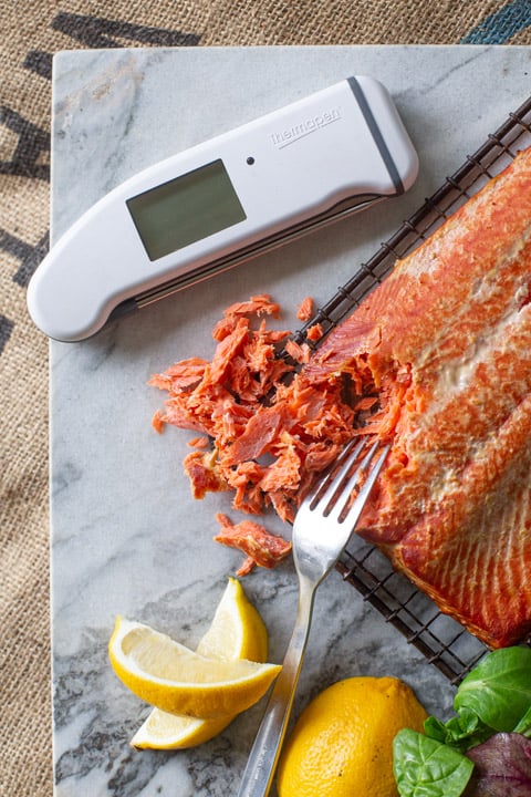 marble chopping board with a fork, hot smoked salmon, lemon wedges and digital thermometer 