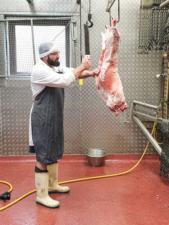 man in stripey apron butchering a salt marsh lamb 