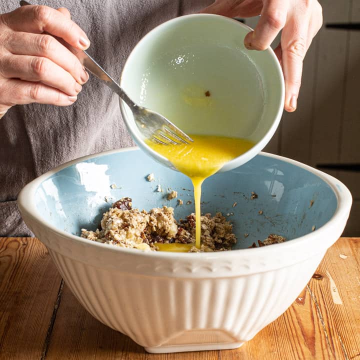 womans hands pouring melted butter into a blue and white mixing bowl