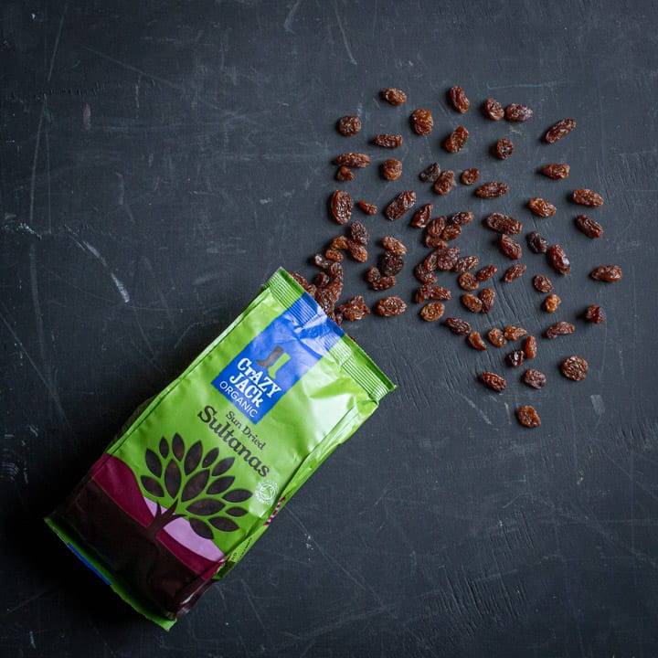 Black background with a bag of Crazy Jack organic sultanas exploding out of the top