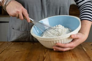 Person holding bowl and whisking flour mixture