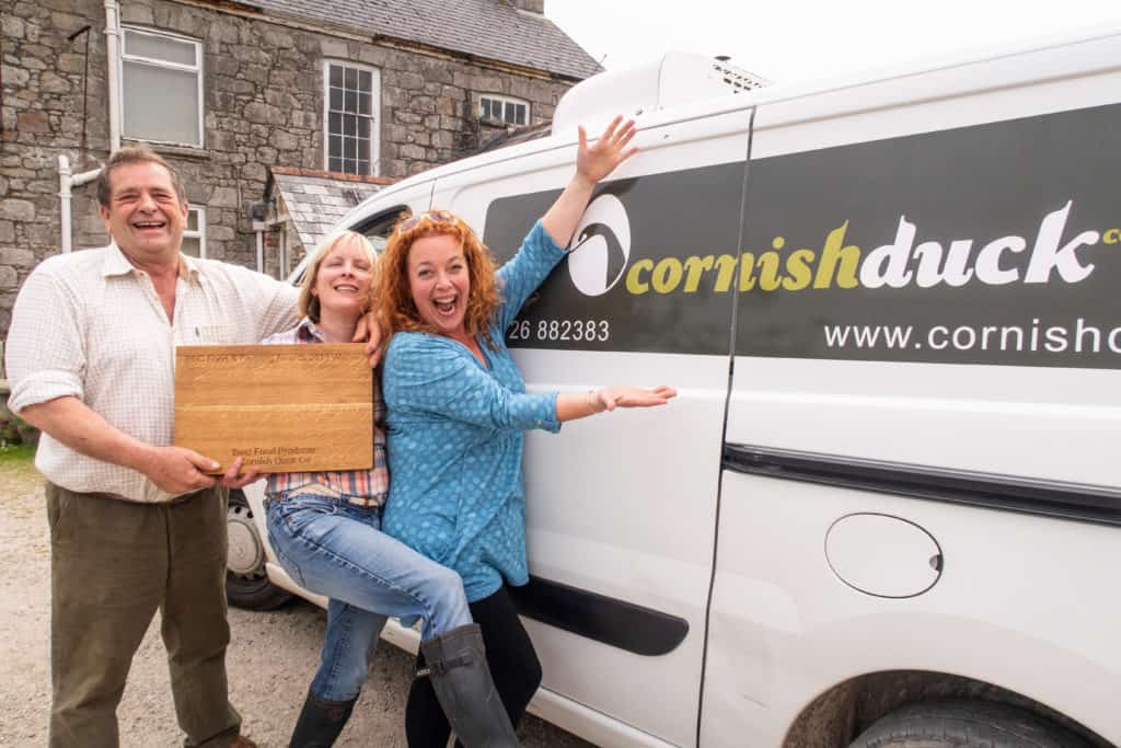 Man and two women holding an award stood by van which say Cornish Duck on it.