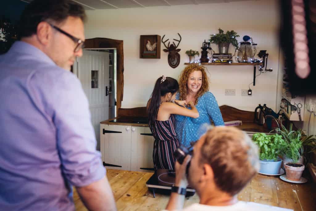 Presenter being mic'd up by a member of a camera crew filming in a kitchen