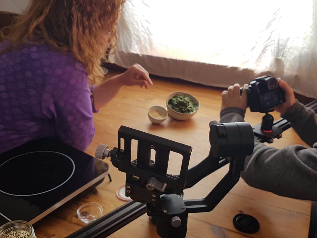 Woman sprinkling ingredients into a bowl in front of a camera. 