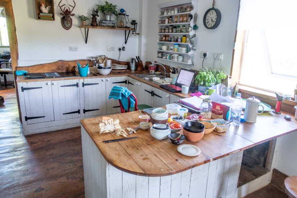 Wooden kitchen with lots of items on the worktop left following cooking session