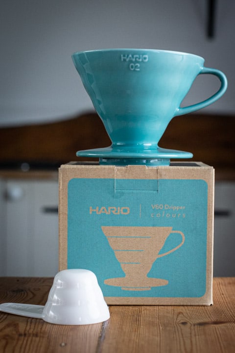 blue hario V60 coffee maker on top of the box with white coffee scoop