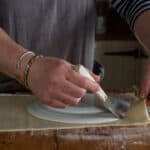womans hands cutting pastry byt running a small knife round a white plate