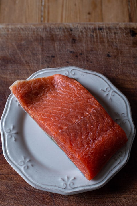 wild salmon fillet on a white plate against a wooden background