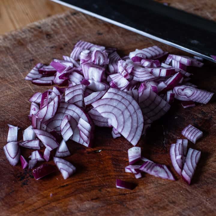 finely diced red onion on a wooden chopping board