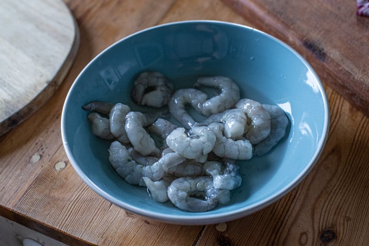 blue bowl of raw grey prawns ready for cooking