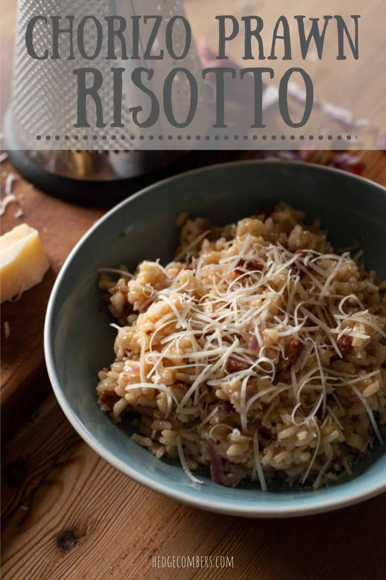 blue bowl of creamy risotto with small pieces of crispy chorizo and juicy prawns with a cheese grater and parmesan rind in the background