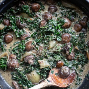 Creamy mushroom stroganoff in a pan with a wooden spoon