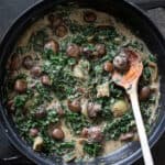 Creamy mushroom stroganoff in a pan with a wooden spoon