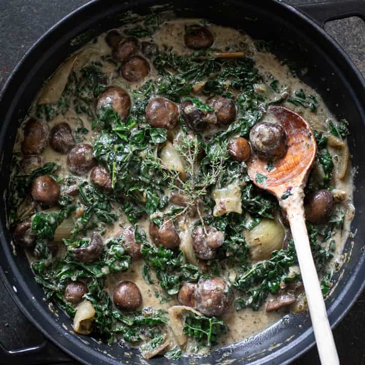 Creamy mushroom stroganoff in a pan with a wooden spoon