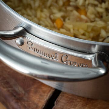 Close up Samual Groves name etched on the handle of a large silver sauce pan on a wooden counter