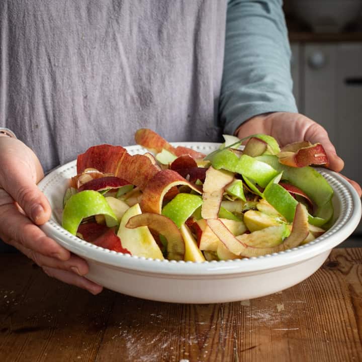 Woman holding a white bowl of apple peels