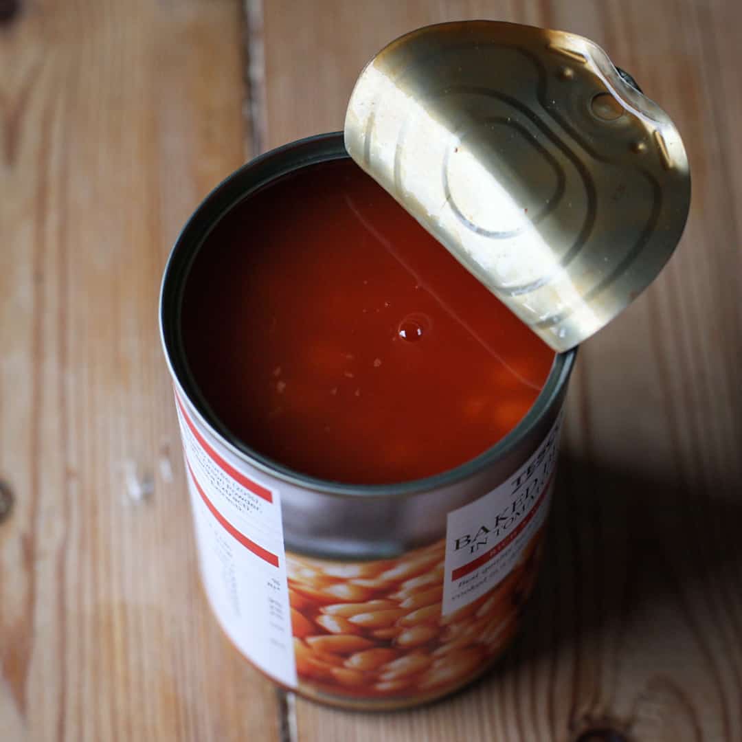 Open can of baked beans on kitchen table