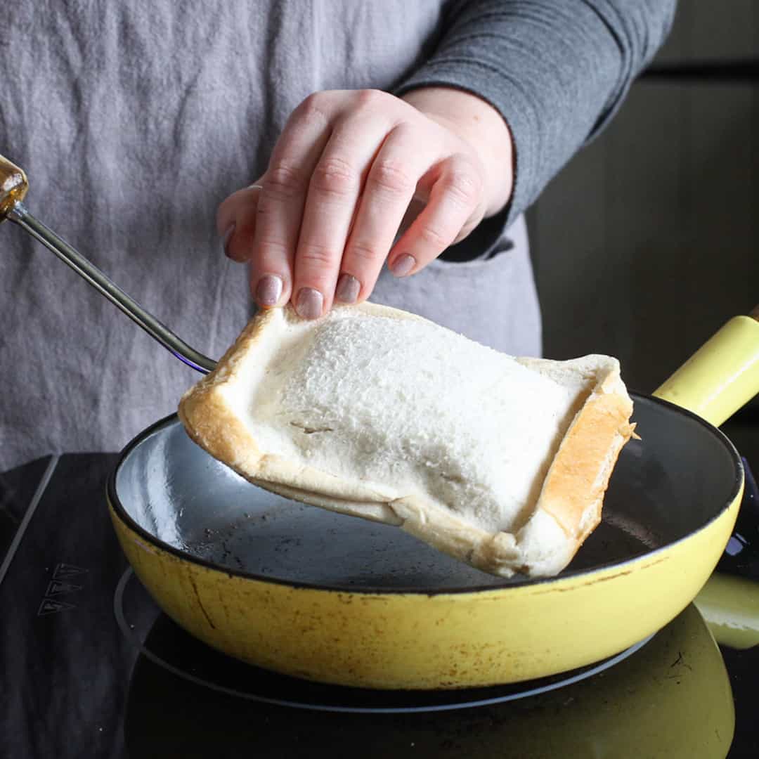 Woman lifting toasty out of frying pan after cooking the first side